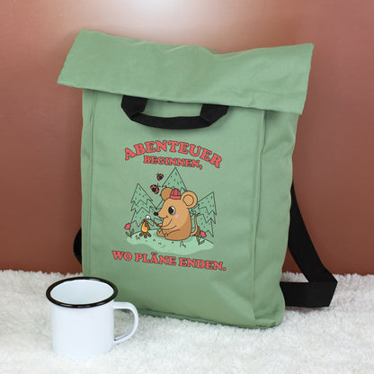 Jadegrüner Rucksack mit Abenteuer-Maus Motiv, Campingmaus, Bergen und Spruch auf flauschigem Untergrund