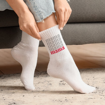 Frau zieht weiße Socken mit Mama Schriftzug in Grau und Rot an, gemütliches Setting