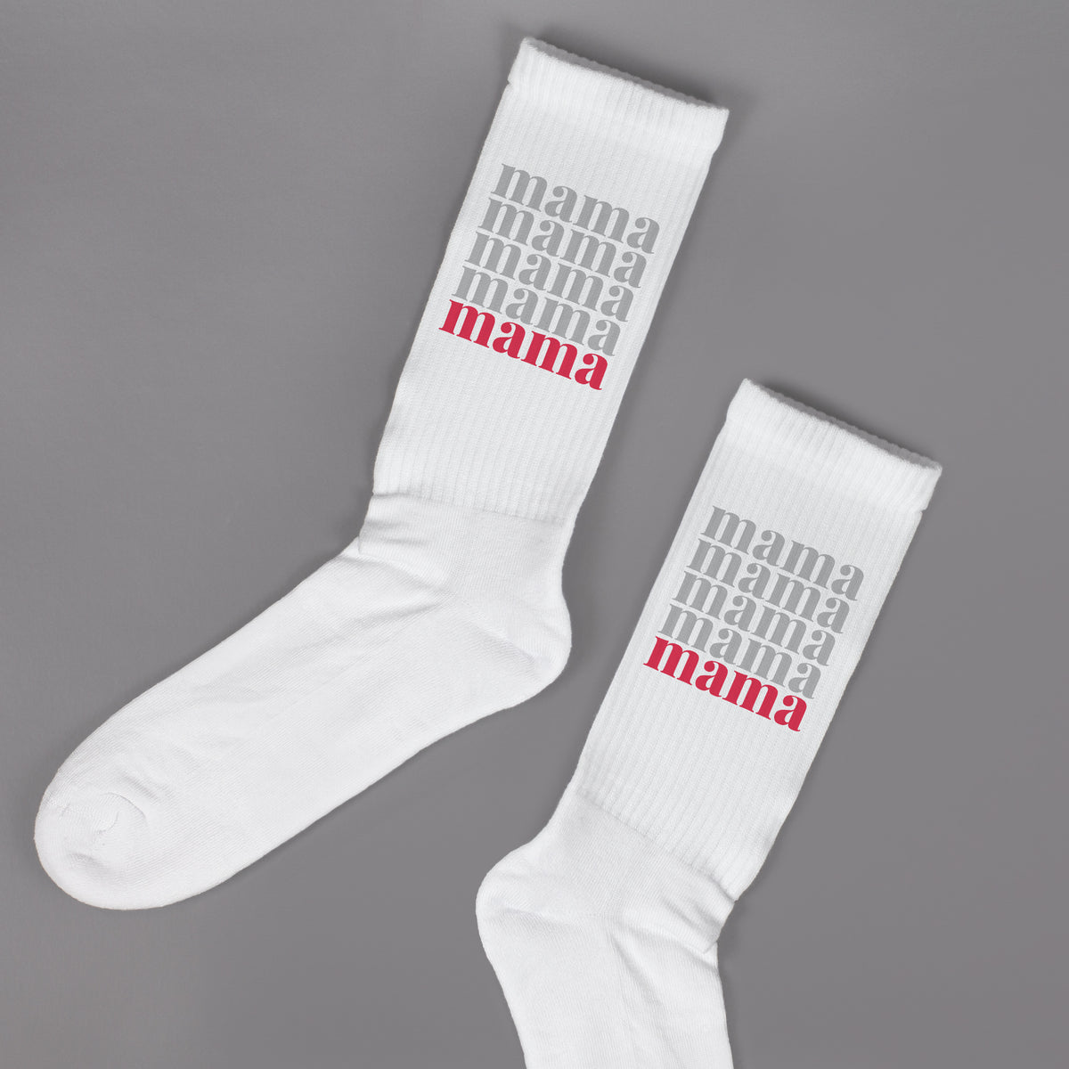 Zwei weiße Socken mit Mama Motiv nebeneinander auf grauem Hintergrund