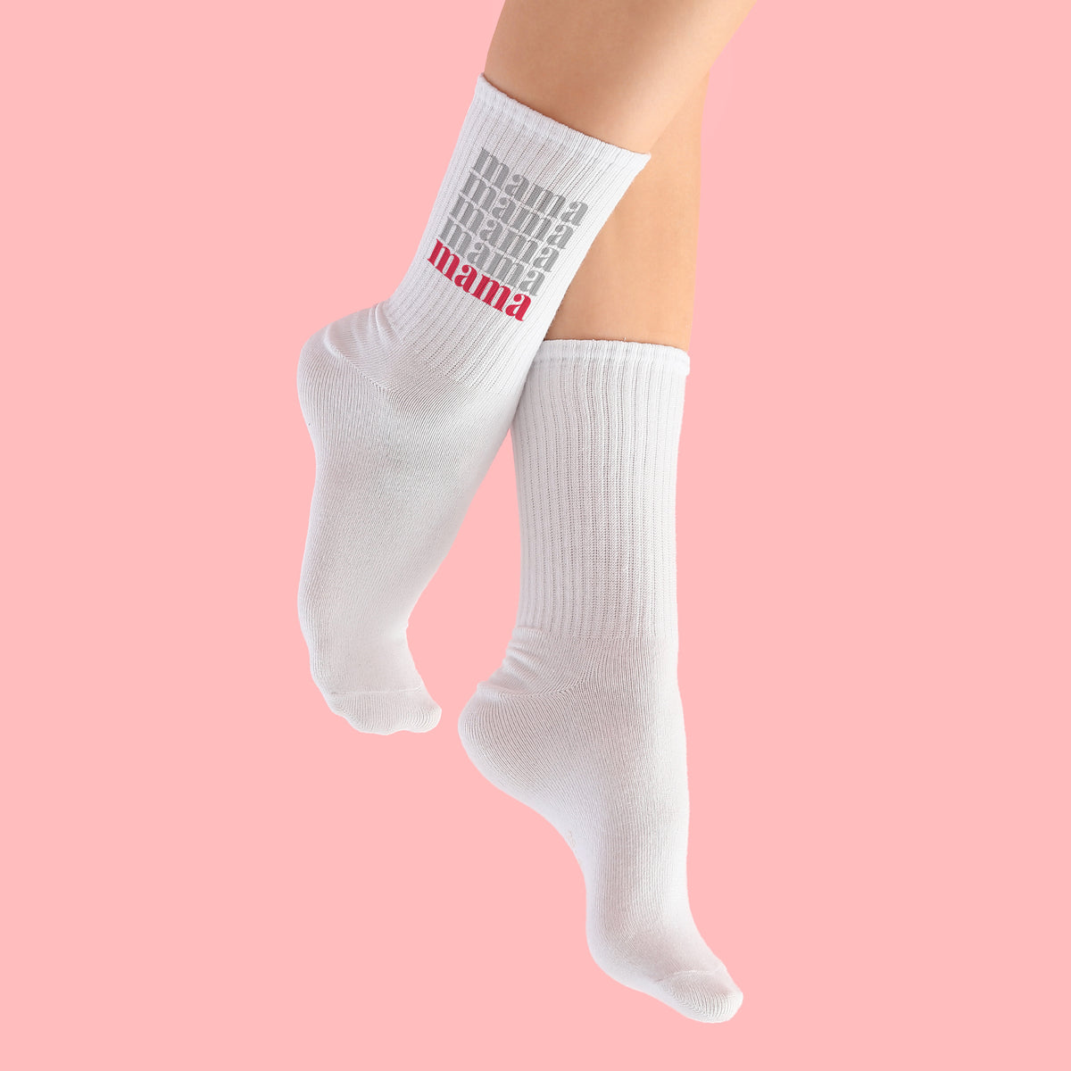 Weiße Socken mit Mama Schriftzug an Füßen vor rosa Hintergrund