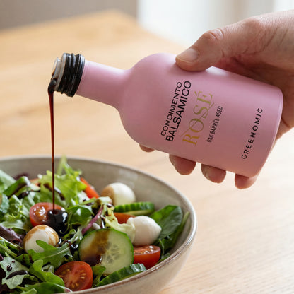 Rosafarbene Balsamico Flasche beim Eingießen über Salat