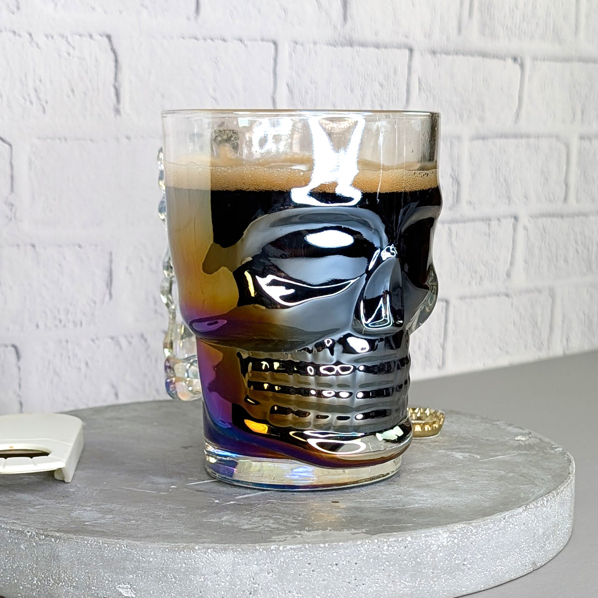 Totenkopfglas leicht schräg von vorne gefüllt mit dunklem Bier und irisierendem Effekt