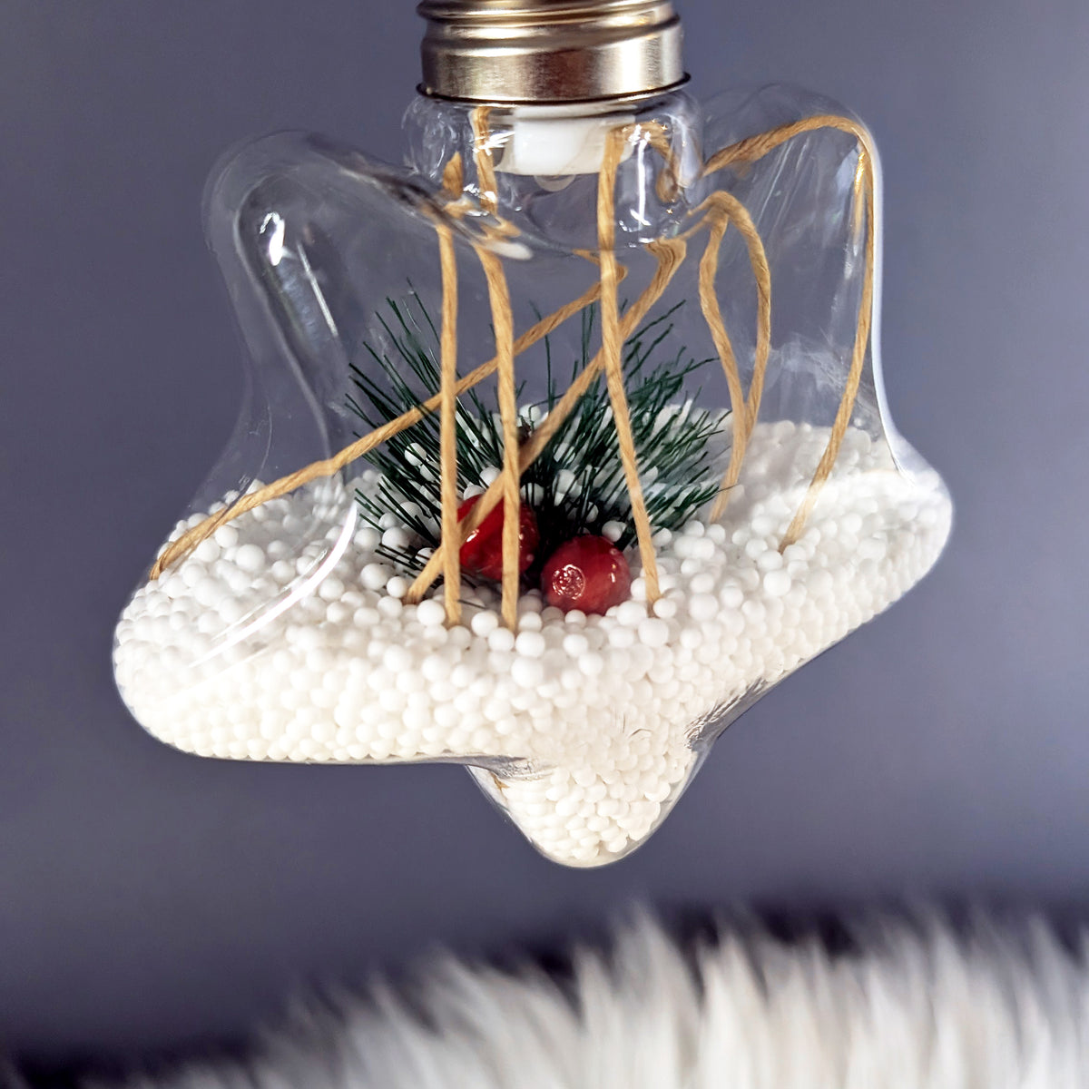 Sternförmige LED-Weihnachtskugel mit Tannenzweig, roten Beeren und warmem Licht.