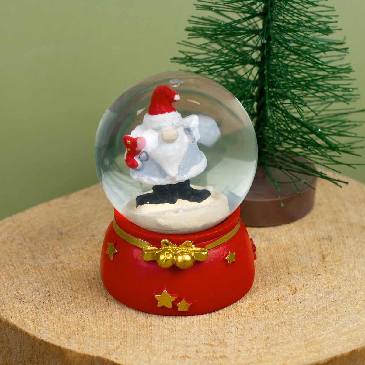 Nahaufnahme der Schneekugel mit Wichtel und Herzmotiv, festliche Dekoration im Hintergrund