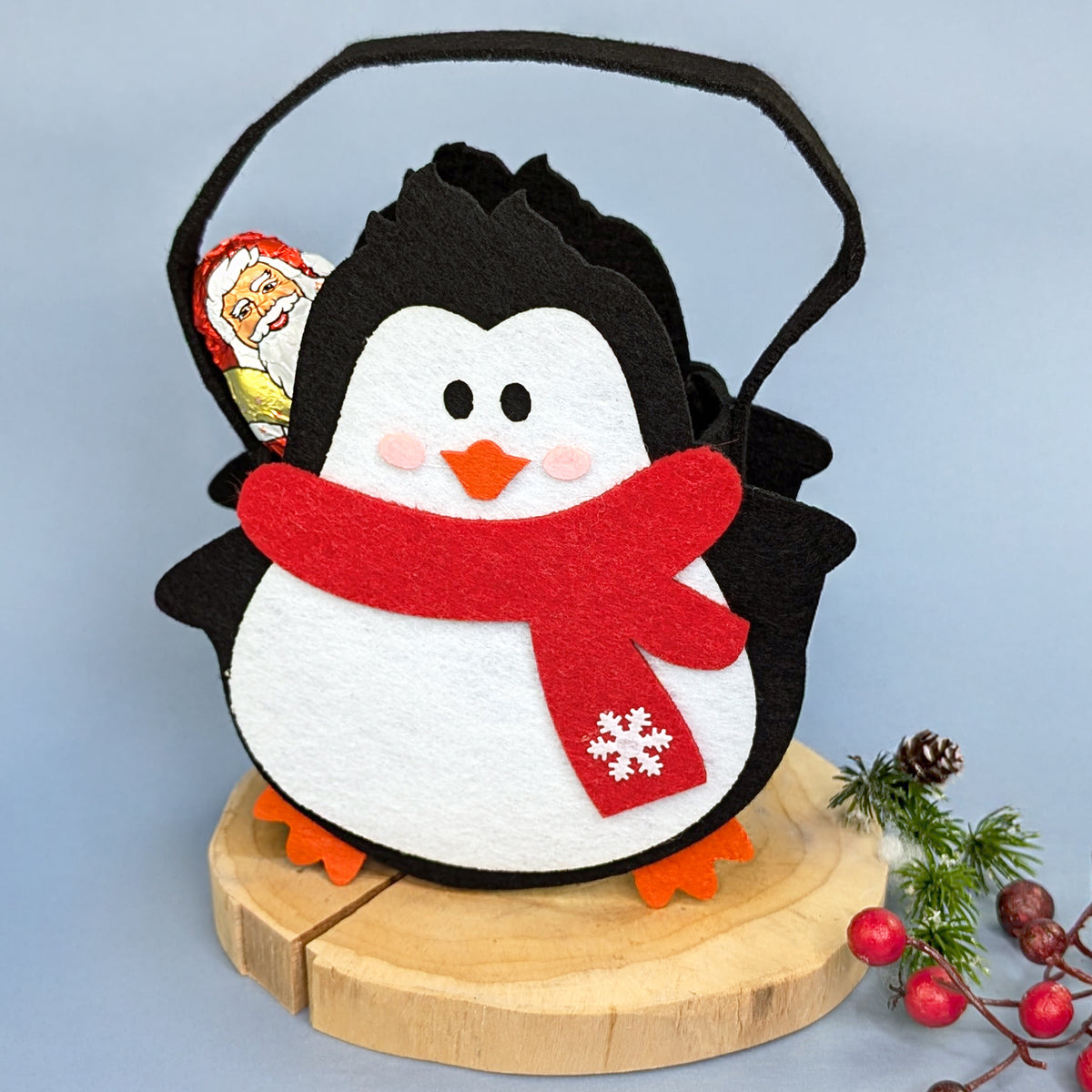 Weihnachts-Geschenktasche aus Filz Motiv Pinguin mit Schal auf Baumscheibe