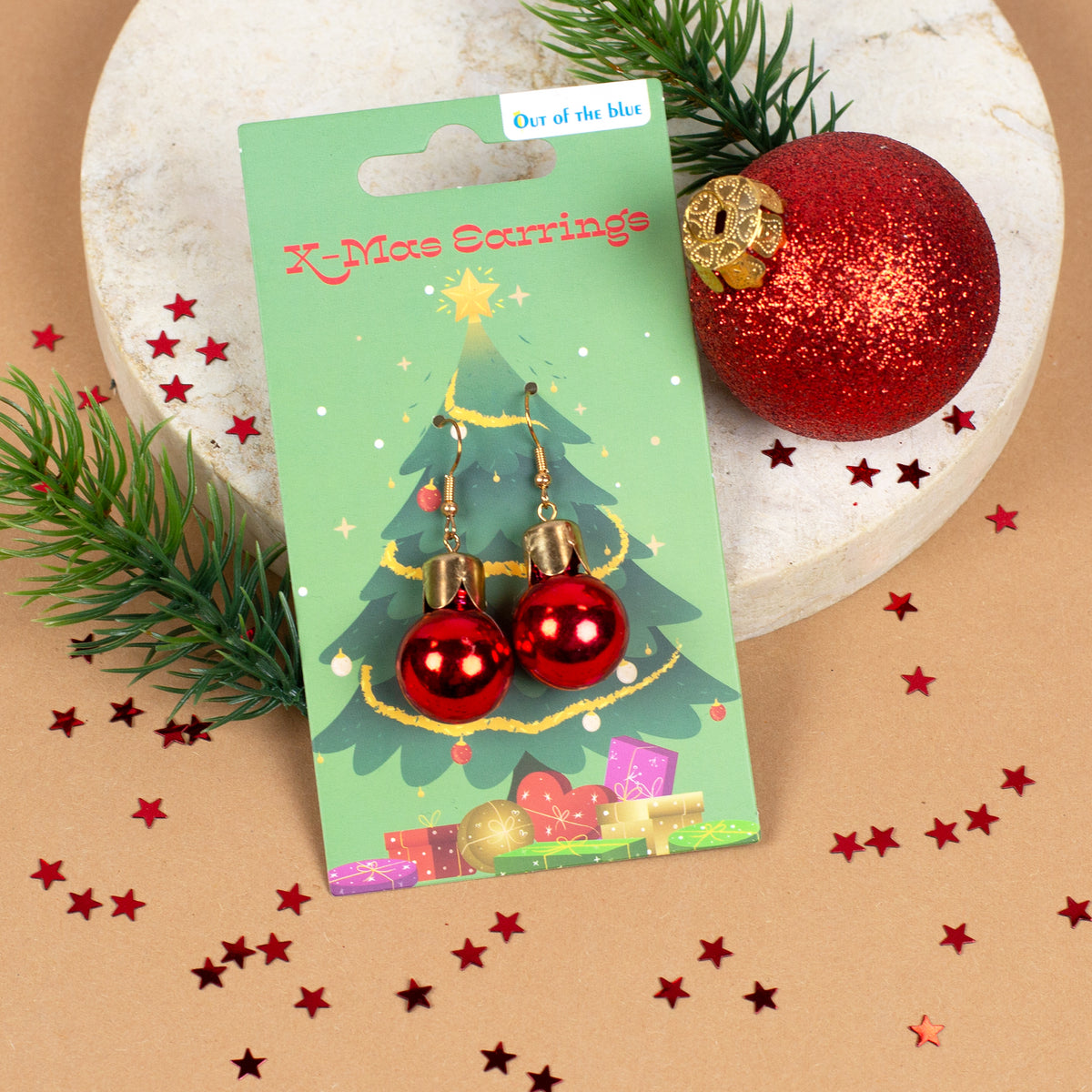 Rote Weihnachtskugel-Ohrringe dekorativ präsentiert neben roten Christbaumkugeln
