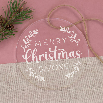 Runde transparente Weihnachtskugel aus Acryl mit „Merry Christmas“, Name Simone, Zweigen und Juteband auf rosa Hintergrund