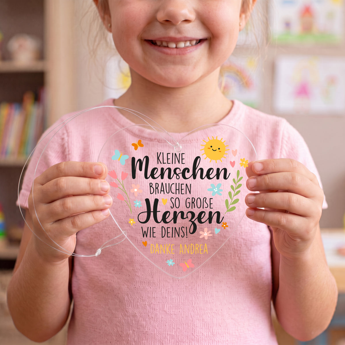 Kind hält transparentes Acrylherz mit Spruch für Erzieher und personalisiertem Text Danke Andrea