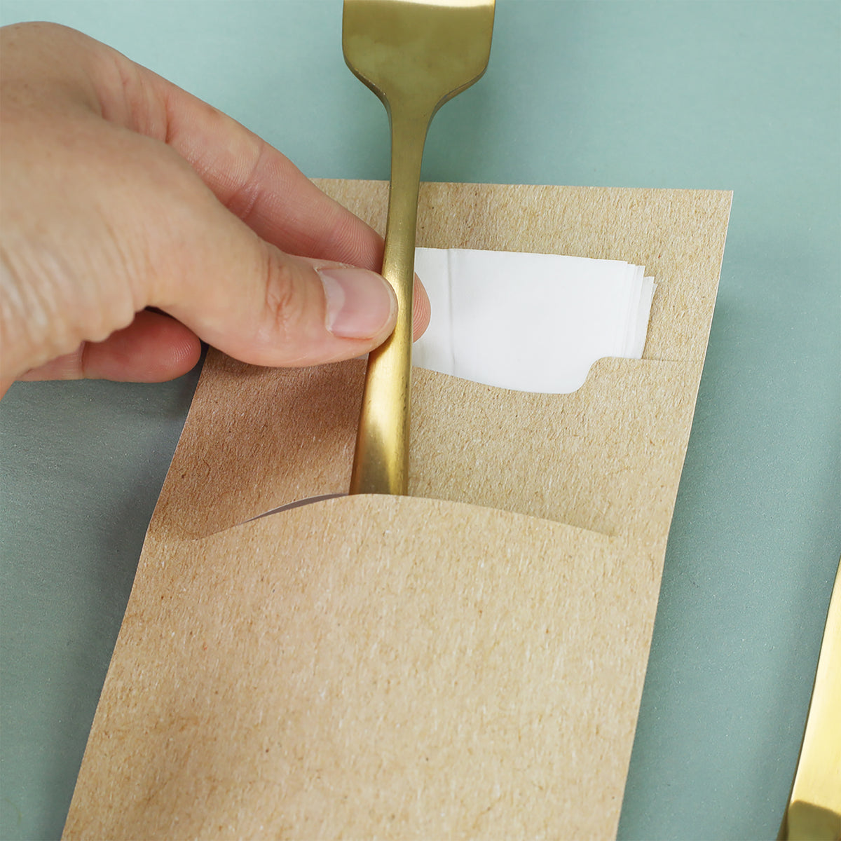 Detailaufnahme Bestecktasche aus Papier mit Serviette und goldener Gabel