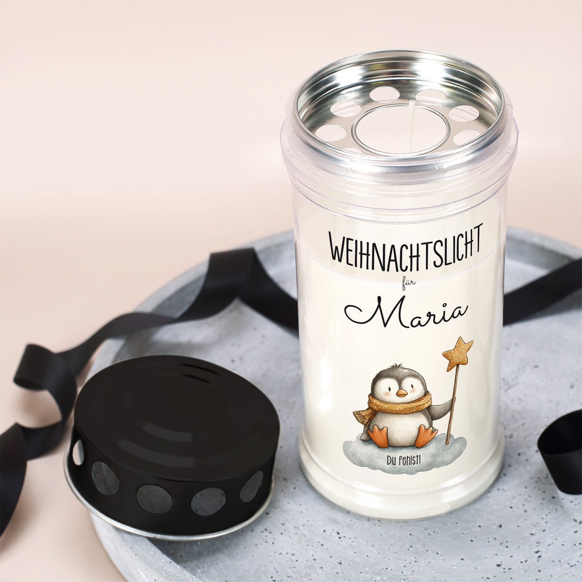 Geöffnetes Weihnachts-Grablicht mit abgenommenem Deckel und Pinguinmotiv, Name Maria, auf Tablett arrangiert
