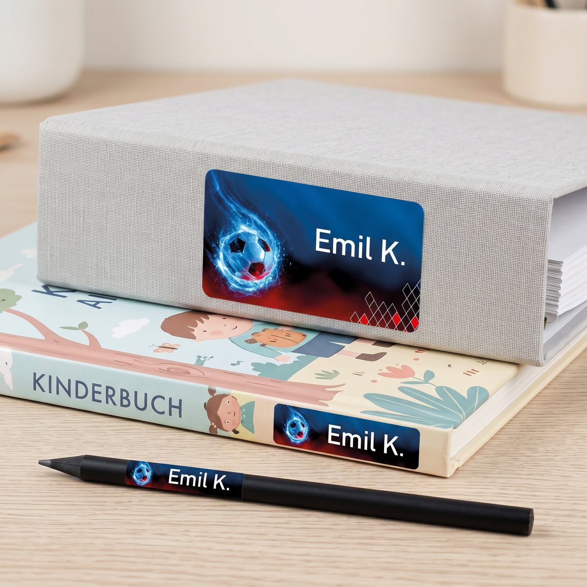 Schulaufkleber mit Fußball-Motiv und Name Emil K. auf Buch, Stift und Aufbewahrungsbox