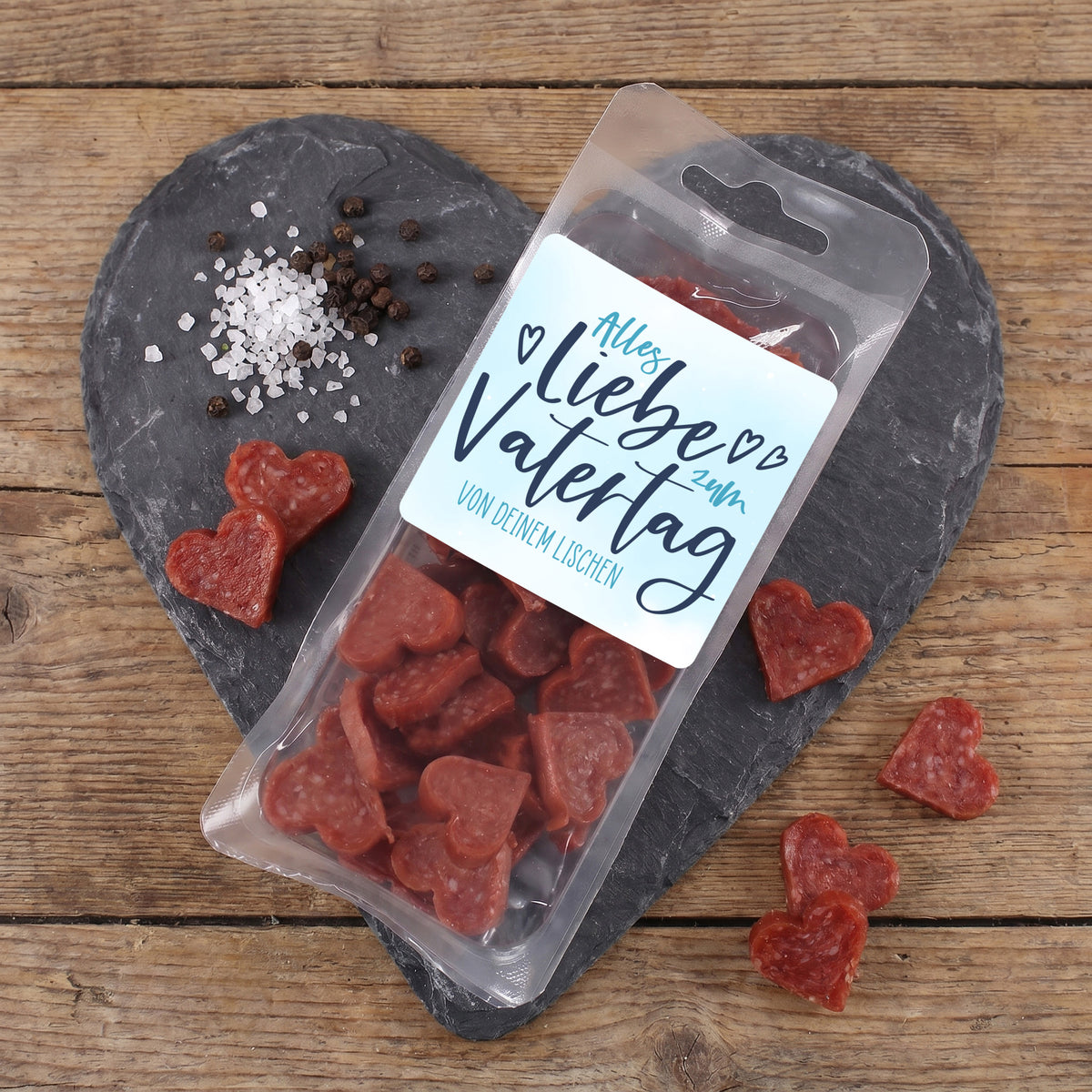 Männerpralinen mit Salami Herzen und personalisiertem Vatertagsetikett auf Schieferplatte mit Gewürzen