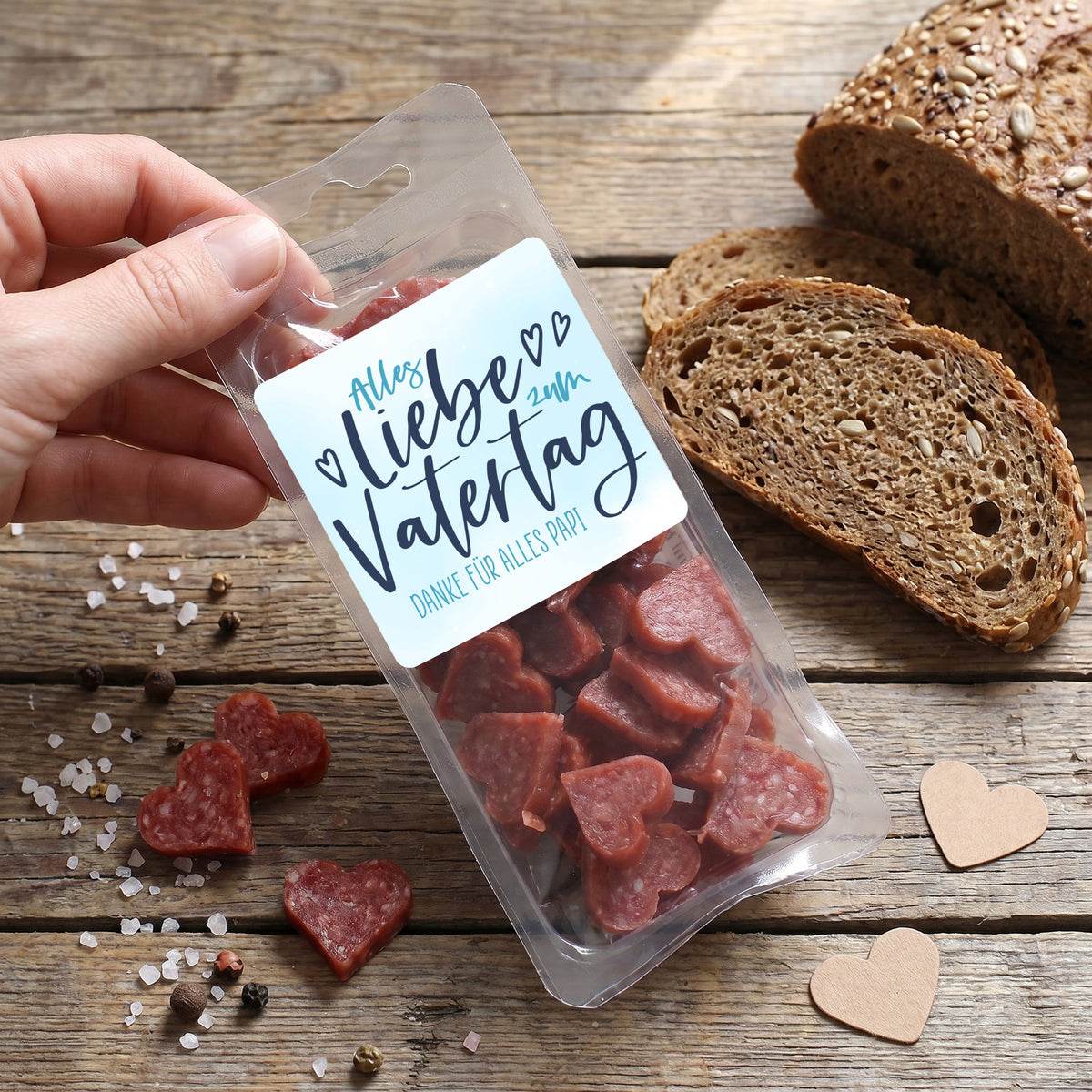 Verpackte Salami Herzen als Geschenk zum Vatertag neben Brot und Gewürzen arrangiert