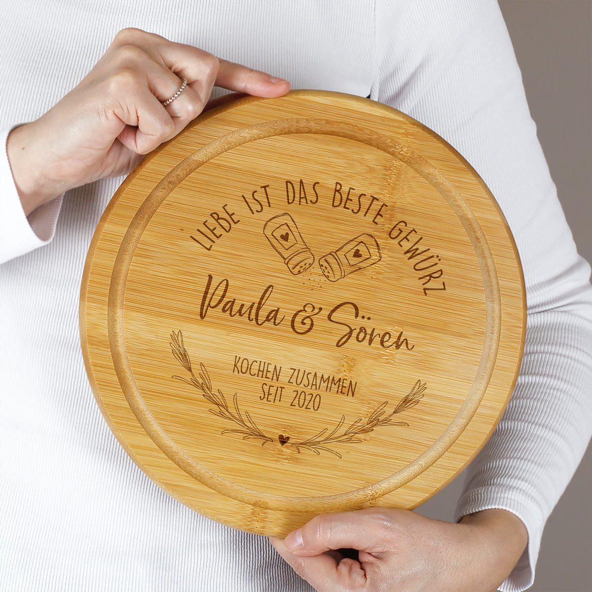 Person hält personalisiertes Bambus Schneidebrett mit Gravur Paula & Sören und „Kochen zusammen seit 2020“