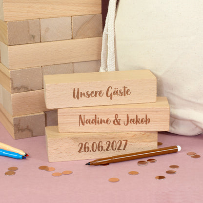 Drei gravierte Holzsteine mit den Aufschriften Unsere Gäste, Namen des Brautpaares und Datum als Personalisierungsbeispiel für das Hochzeitsgästebuch