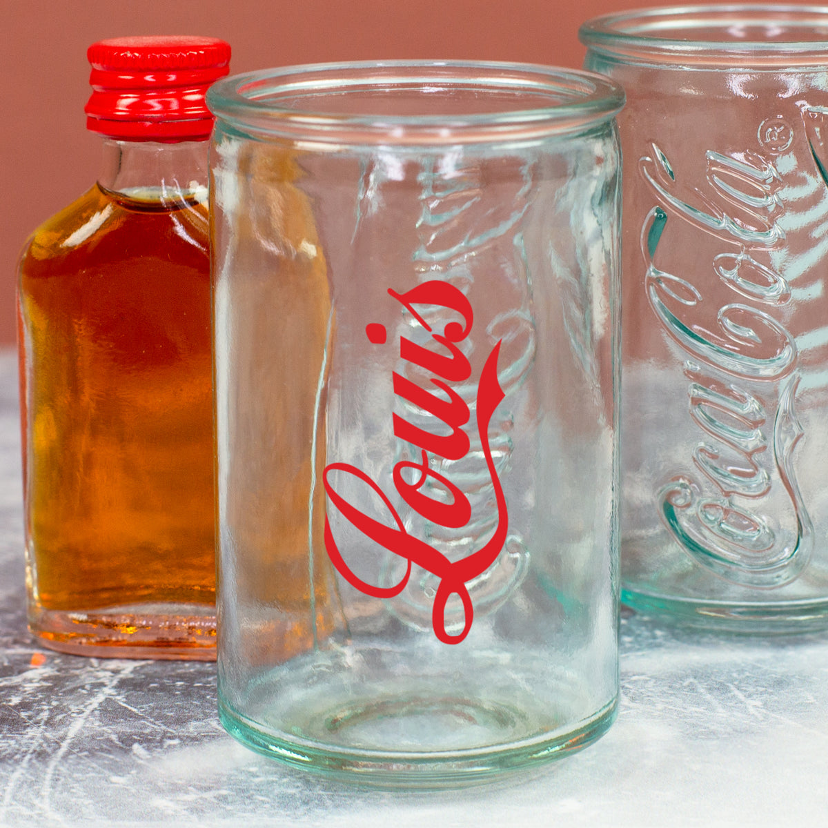 Detailaufnahme vom Coca-Cola Shotglas mit rotem Namen Louis und durchscheinendem geprägtem Logo
