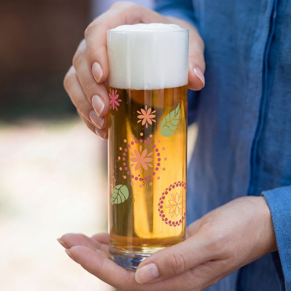 Personalisiertes Bierglas mit floralem Ornament-Motiv und Name, in beiden Händen gehalten