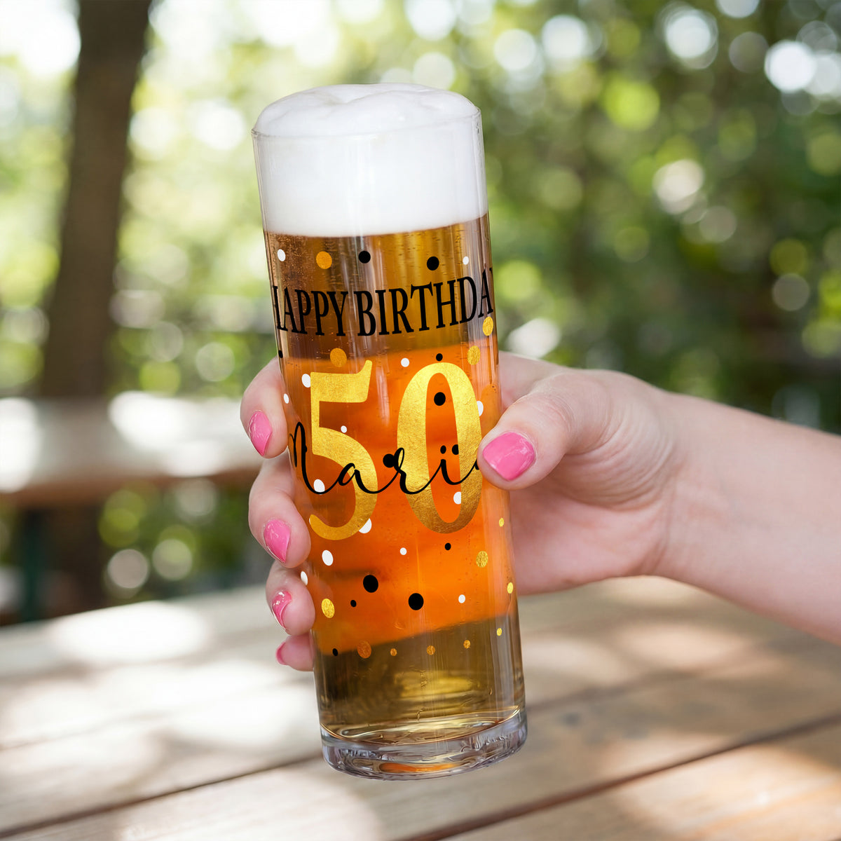 Geburtstags-Kölschglas mit großer goldener Zahl 50 und personalisiertem Namen, gehalten in einer Hand, gefüllt mit Bier und Schaum.