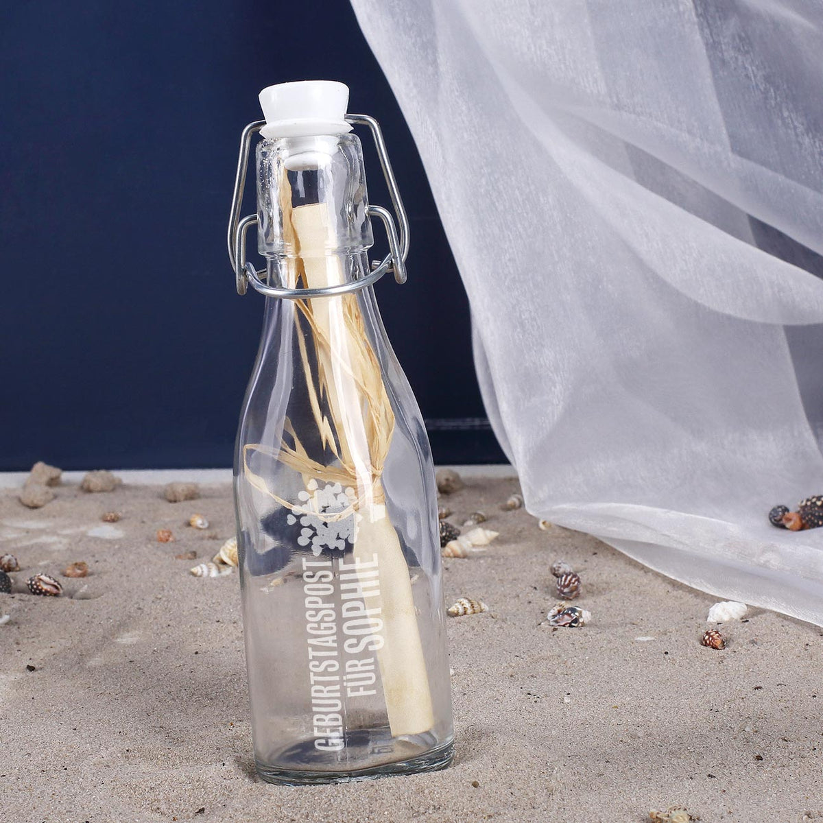 Glasflasche mit Bügelverschluss und eingerollter Geburtstagspost auf weißem Hintergrund als Geschenkidee