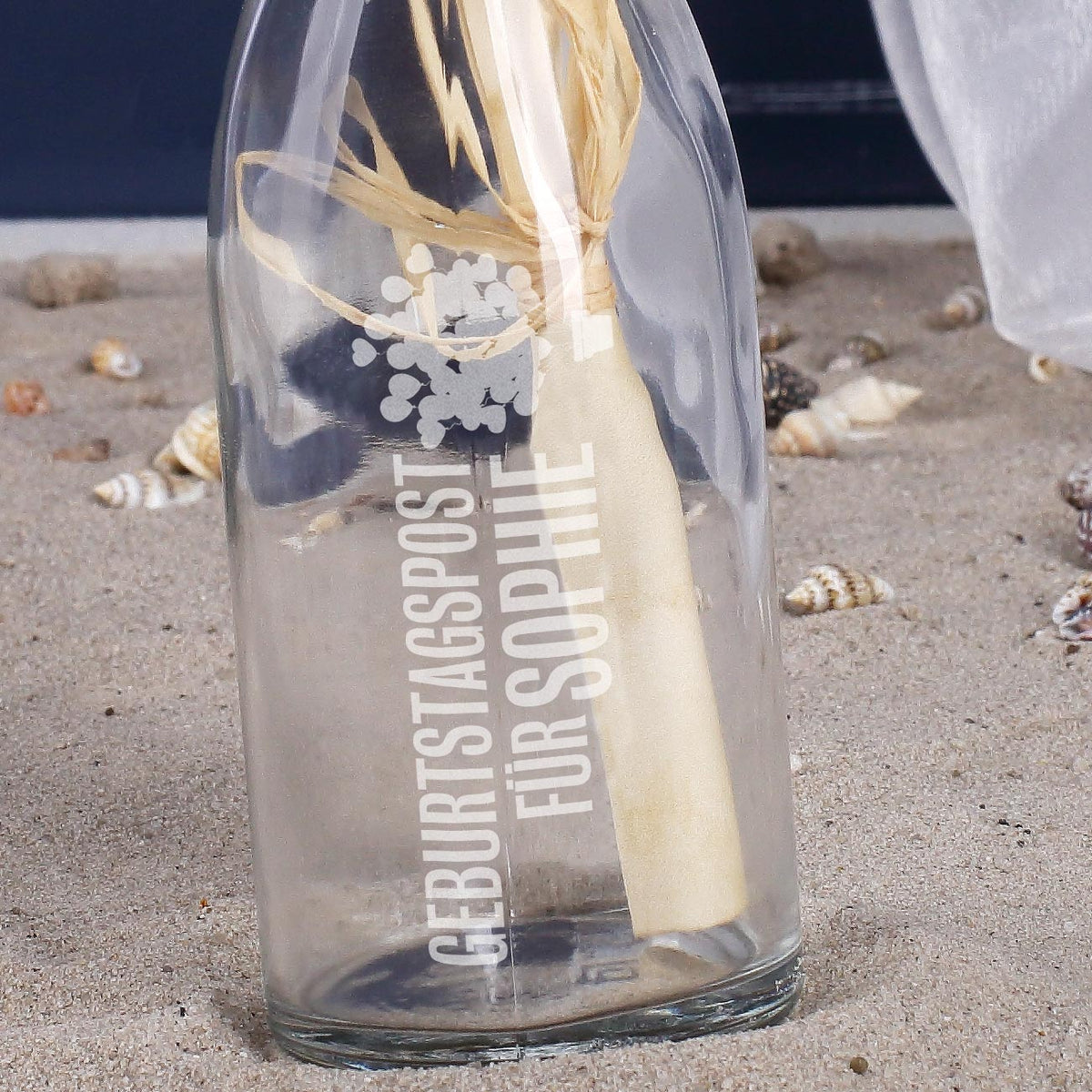 Detailansicht einer Glasflasche mit Geburtstagspost für Sophie, dekoriert mit Sand und Muscheln im maritimen Stil