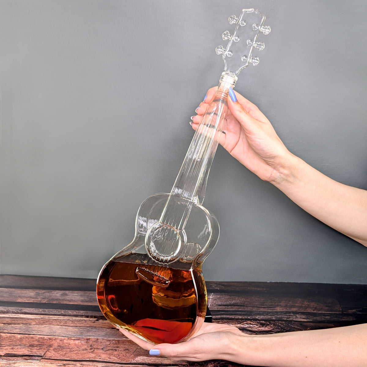 Karaffe in Gitarrenform gehalten von zwei Händen