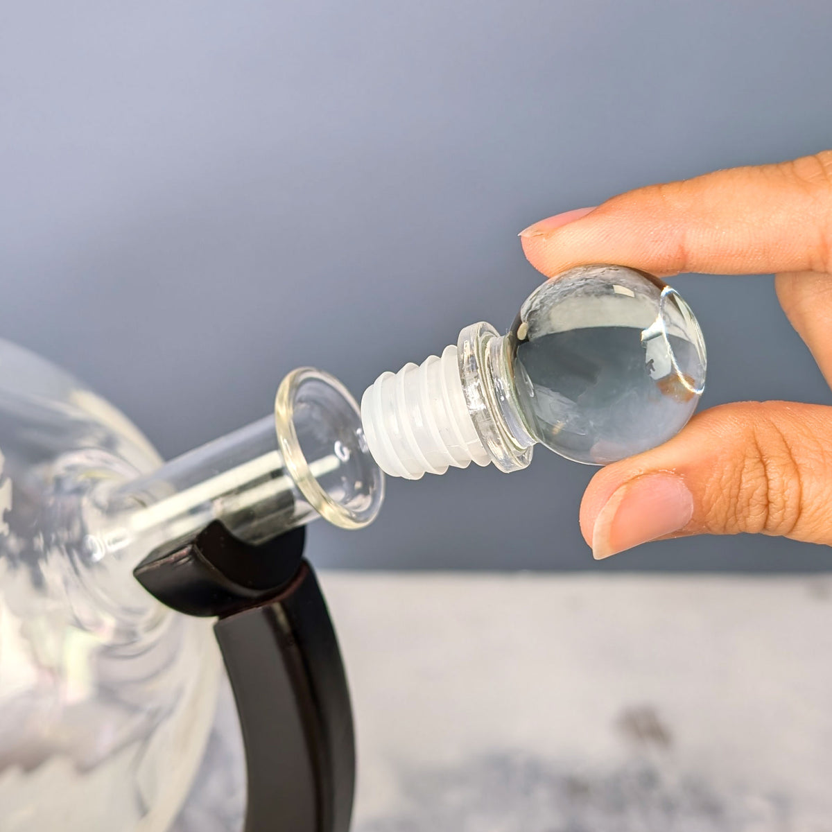 Glas-Aromaverschluss mit Dichtung wird in den Flaschenhals des Dekanters eingesetzt – Hand hält Verschluss