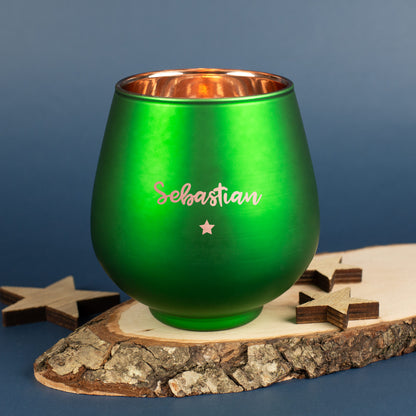Grünes Windlicht mit Gravur „Sebastian“ und Sternmotiv, auf Holzscheibe mit Sternendeko.