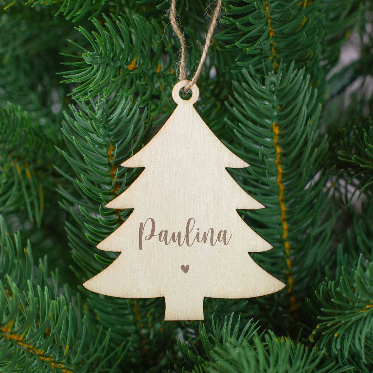 Tannenbaum-Anhänger aus Holz mit Gravur „Paulina“ und Herzsymbol, aufgehängt im Christbaum.