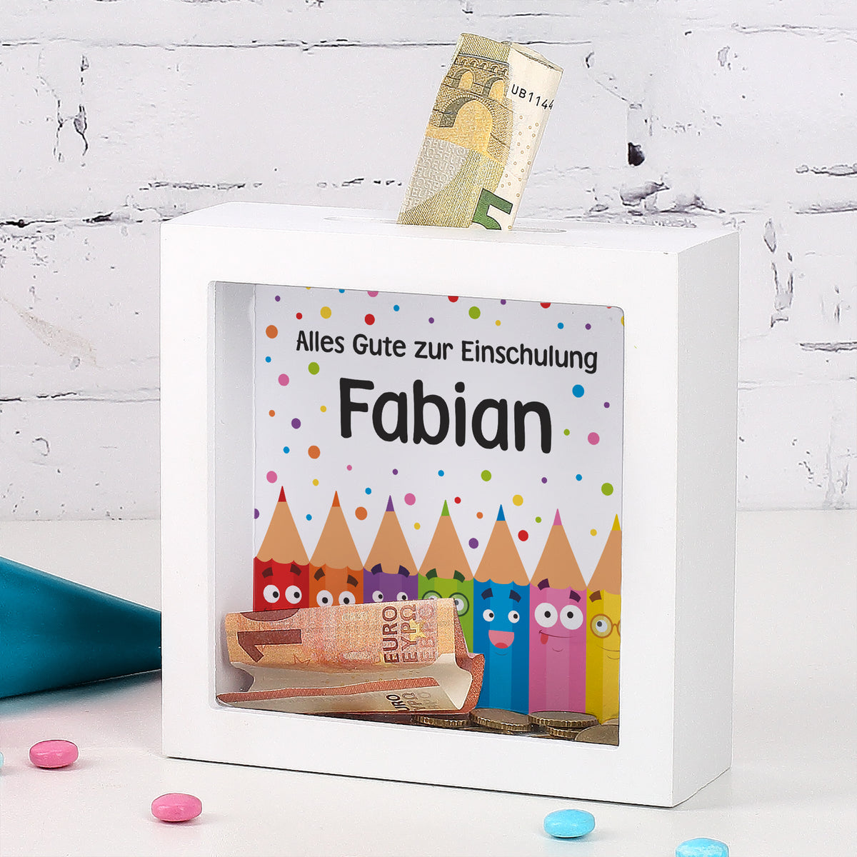 Weiße Bilderrahmen-Spardose zur Einschulung mit Name Fabian, Geldscheinen und buntem Schulmotiv