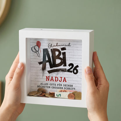 Personalisierte Spardose mit Abi 26 Motiv und Name Nadja, in beiden Händen gehalten