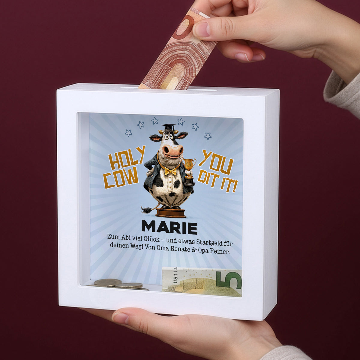 Hand steckt Geldschein in personalisierte Bilderrahmen-Spardose mit Name Marie zum bestandenen Abitur