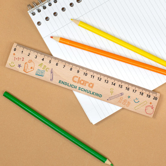 Personalisiertes Lineal aus Holz mit Name Clara und Text „Endlich Schulkind“ auf Notizblock mit Stiften