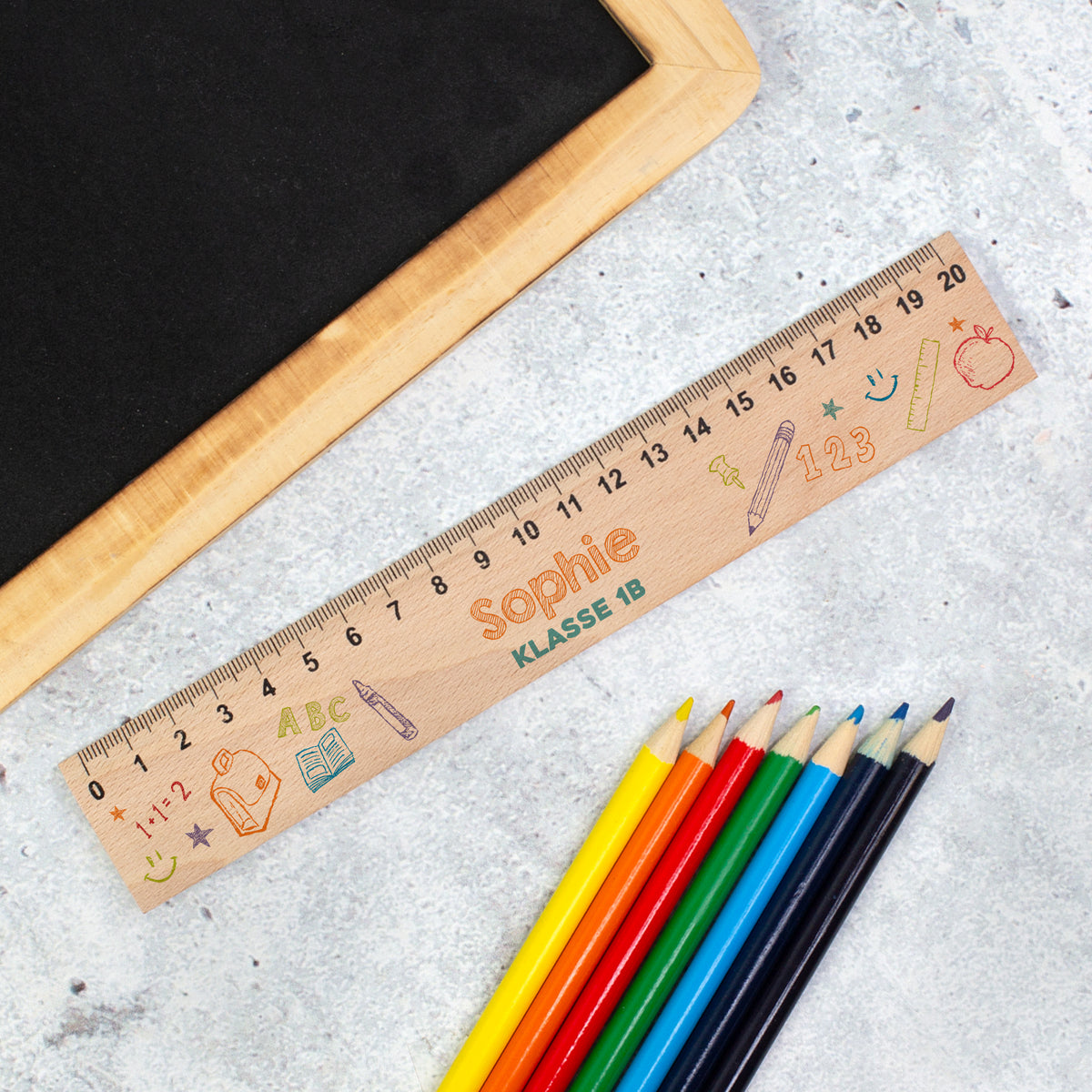 Personalisiertes Holzlineal zur Einschulung mit Name Sophie und Text „Klasse 1B“ neben bunten Stiften
