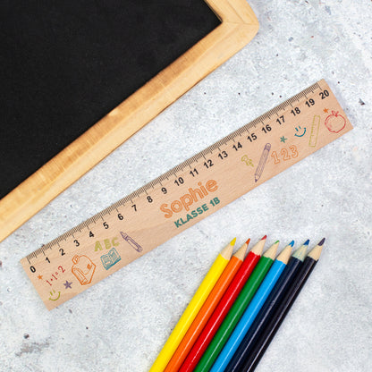 Personalisiertes Holzlineal zur Einschulung mit Name Sophie und Text „Klasse 1B“ neben bunten Stiften