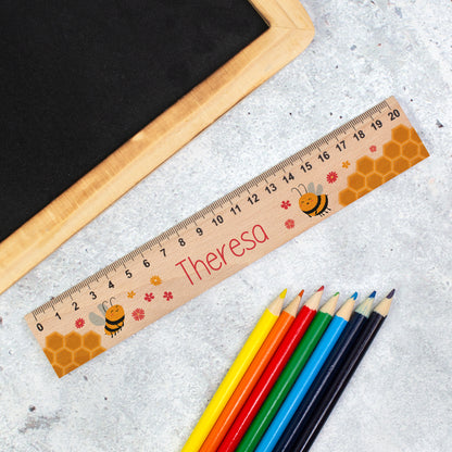Personalisiertes Holzlineal mit Bienenmotiv und Name Theresa neben bunten Stiften zur Einschulung