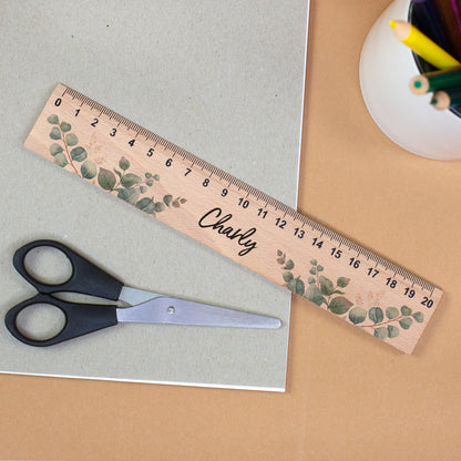 Personalisiertes Holzlineal mit Eukalyptusmotiv und Name Charly neben Schere und Stiftehalter
