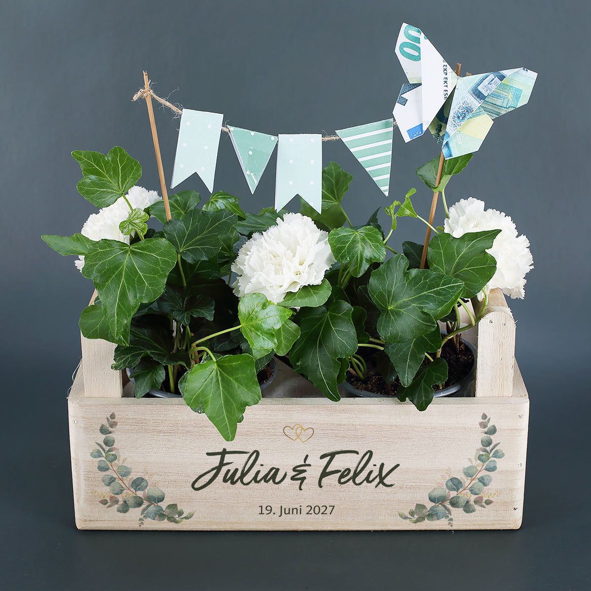 Pflanzkorb zur Hochzeit mit Efeu, weißen Blumen, Wimpelkette und Geldschein-Schmetterling
