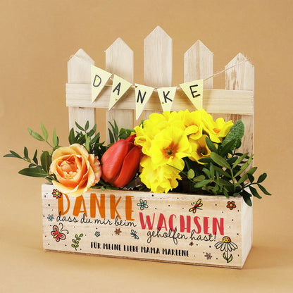 Dekorierte Pflanzkiste mit bunten Blumen und dem Zusatz „Für meine liebe Mama Marlene“ unter dem Dankesspruch