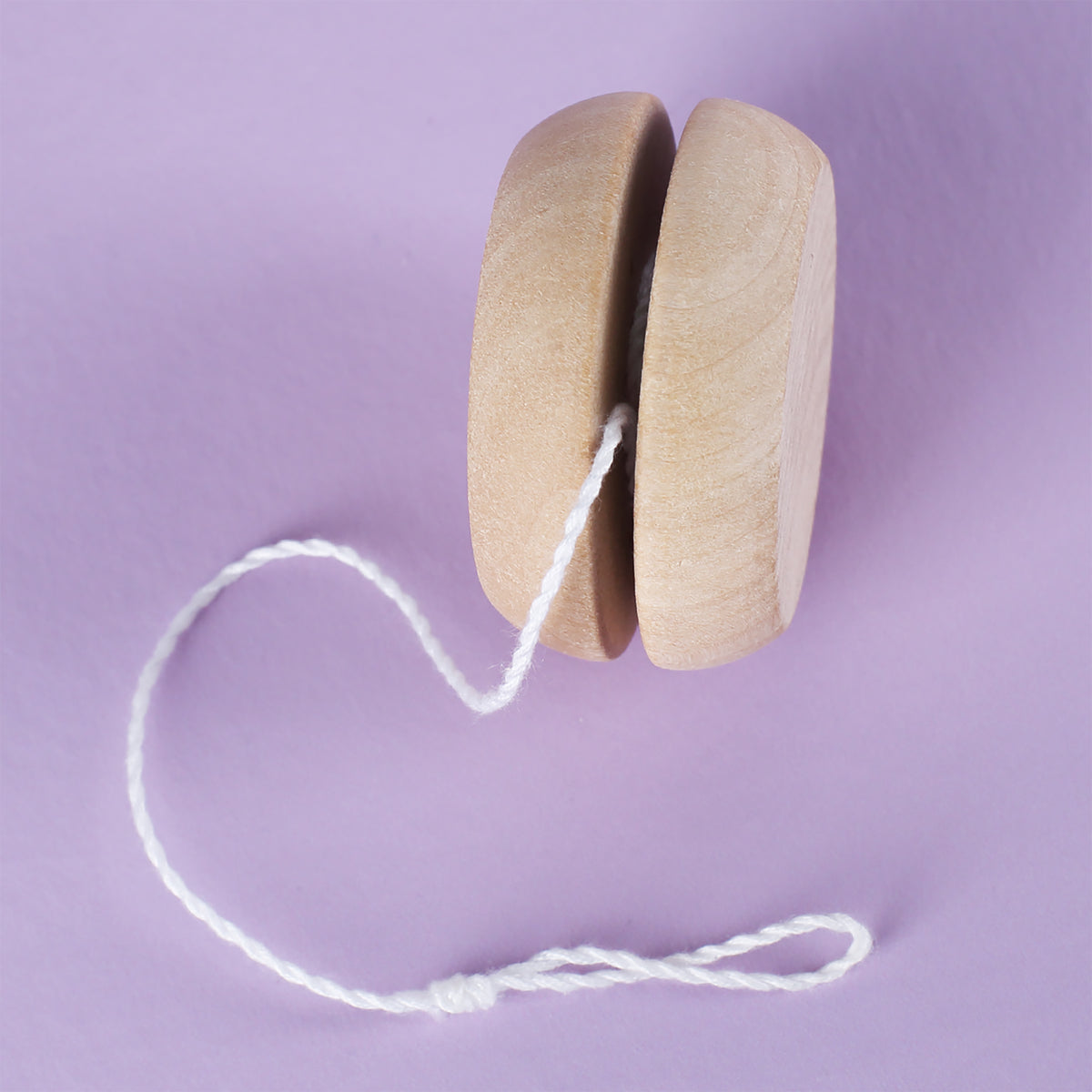 Seitenansicht eines natürlichen Holz-Yo-Yos mit aufgewickelter weißer Schnur