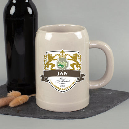 Personalisierter Steingut Bierkrug mit Name Jan und Wappenmotiv neben schwarzer Flasche auf Schieferplatte