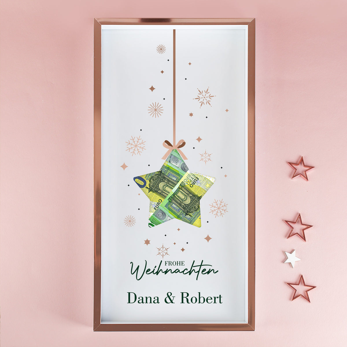 Geldgeschenk Bilderrahmen zu Weihnachten mit Namen Dana und Robert, Stern-Aussparung und Euro-Scheinen vor rosa Wand