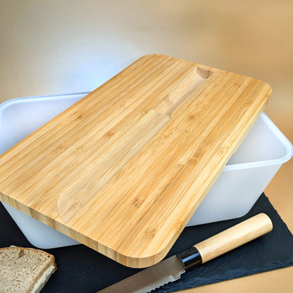 Geöffneter Brotkasten mit seitlich aufliegendem Bambusdeckel und Messer
