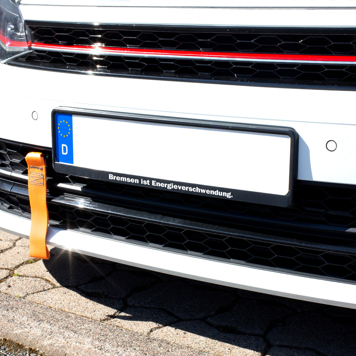 Schwarzer Kennzeichenhalter am Auto mit individuellem Spruch „Bremsen ist Energieverschwendung“