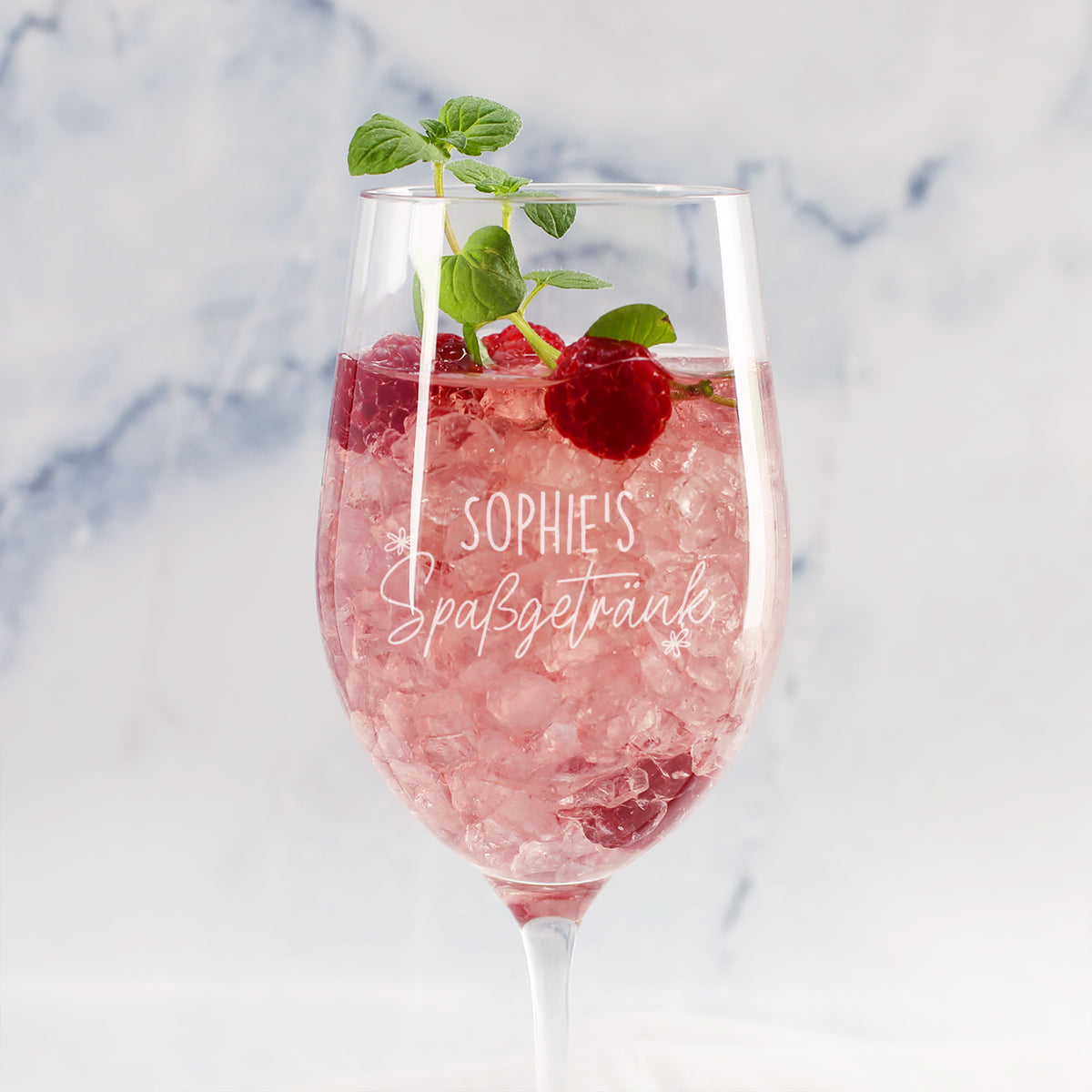 Personalisiertes Weinglas mit Gravur Sophies Spaßgetränk, rosa Drink, Himbeeren und Minze vor hellem Hintergrund