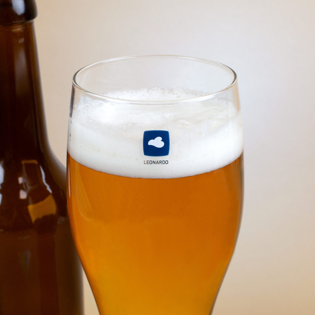 Detailaufnahme Weizenglas von Leonardo mit Logo am oberen Rand, gefüllt mit Bier