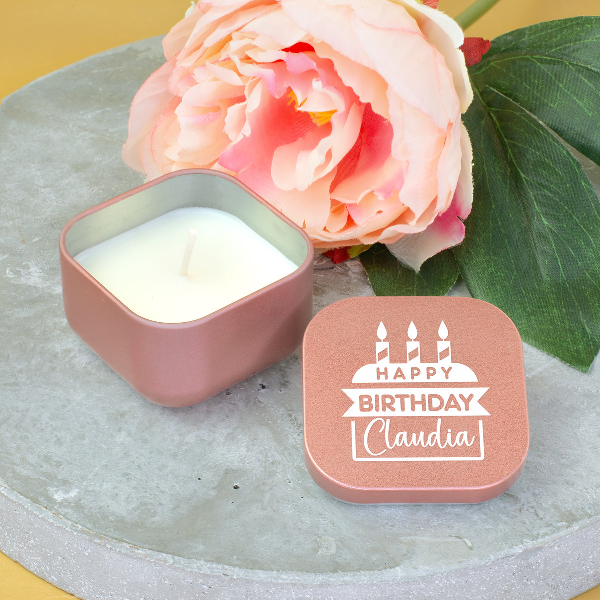 Personalisierte Geburtstags Duftkerze in Roségold mit Name Claudia neben rosa Blume dekoriert