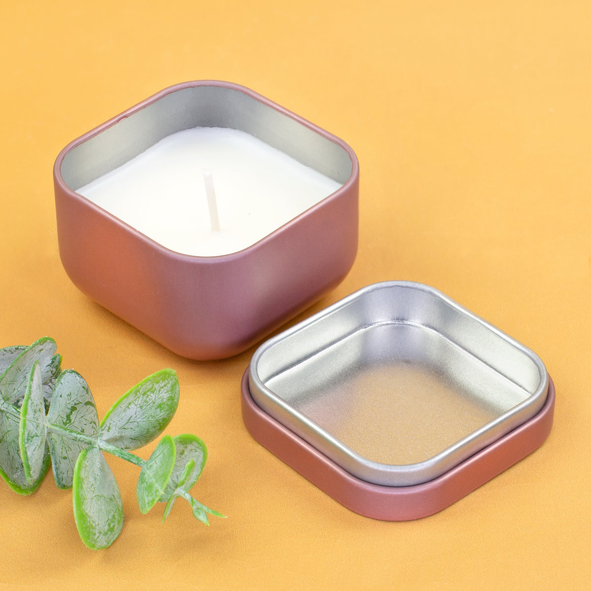 Geöffnete Mini Duftkerze in Roségold mit Metalldeckel und Vanillewachs auf gelbem Hintergrund