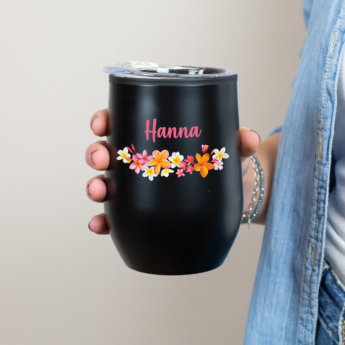 Variante: Schwarzer Thermobecher mit Blumenmuster und Name Hanna in Frauenhand gehalten