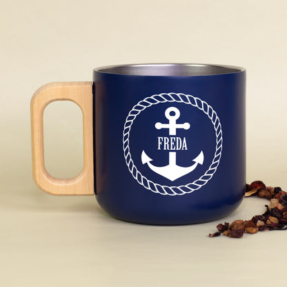 Personalisierter dunkelblauer Edelstahlbecher mit Holzgriff, Anker-Motiv und Name Katrin auf kariertem Stoff