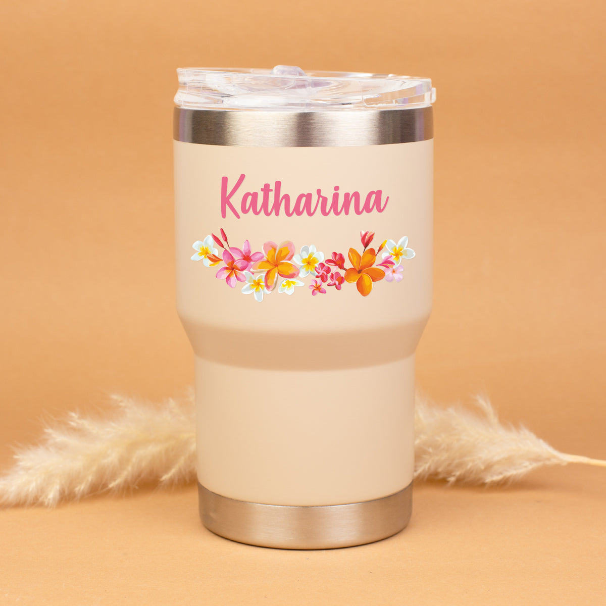 Beigefarbener Thermobecher mit buntem Blumenmotiv und Name Katharina personalisiert vor warmem Hintergrund
